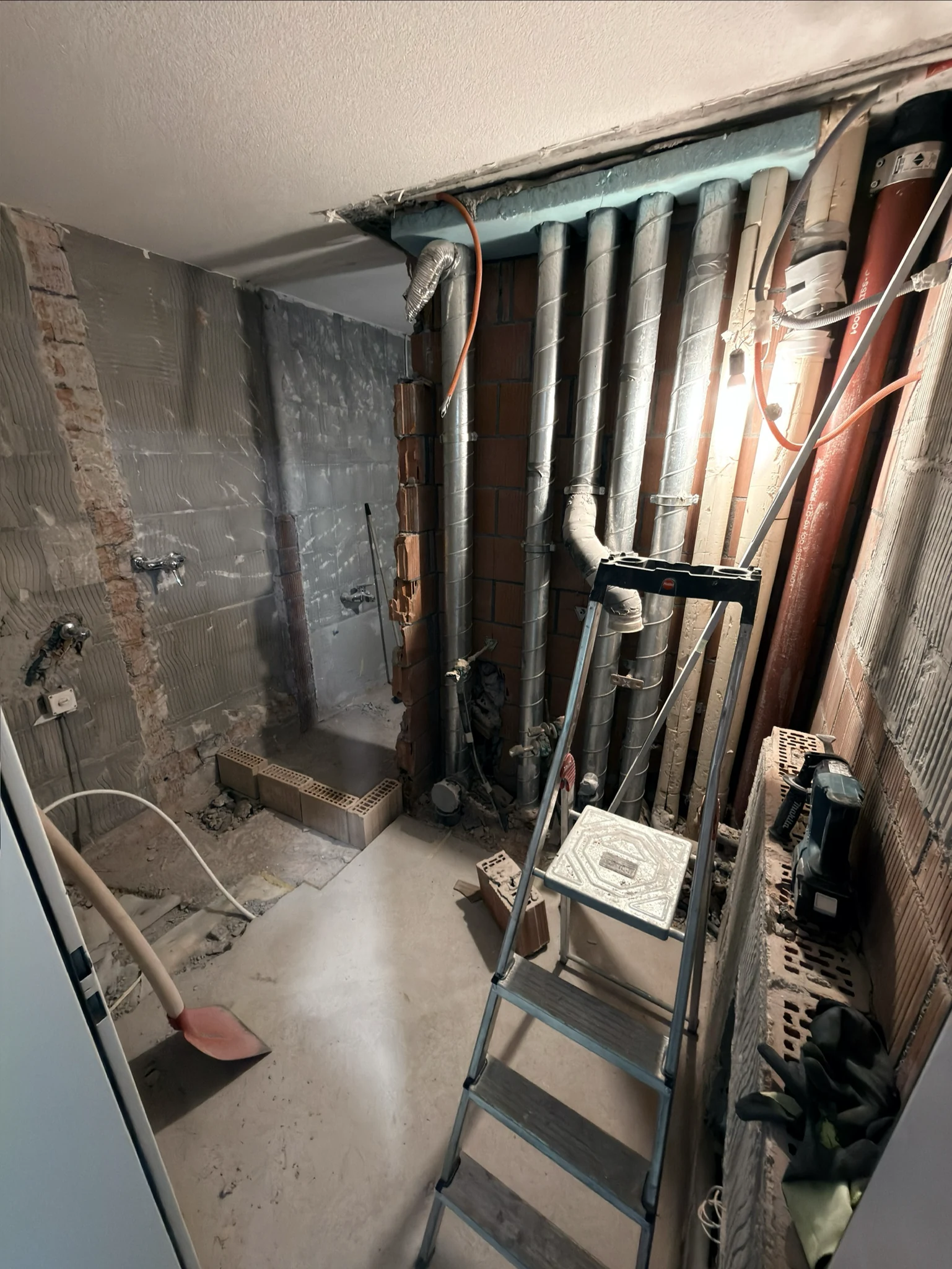 Freigelegte Sanitärleitungen und WC-Vorwandelement im Badezimmer während des Umbaus