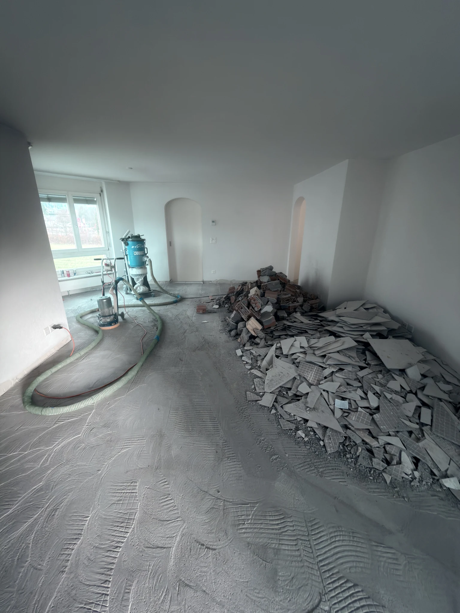 Wohnraum während des Bodenrückbaus mit Bauschutt und Absaugschläuchen